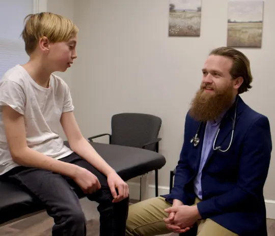 Osteopathic Dr consulting with a boy in an exam room